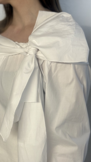 Descubre la versatilidad de nuestra camisa blanca con lazada larga y botones de perla. Un diseño multiposición en algodón elástico para un estilo único.