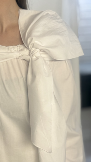 Descubre la versatilidad de nuestra camisa blanca con lazada larga y botones de perla. Un diseño multiposición en algodón elástico para un estilo único.