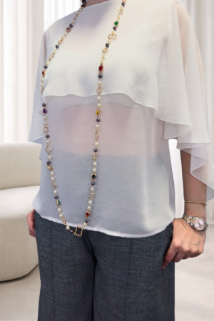 Camisa de gasa blanca para mujer de OH.LA con diseño de volantes superpuestos, mangas murciélago y escote en la espalda. Prenda femenina elegante y versátil para un fondo de armario atemporal.