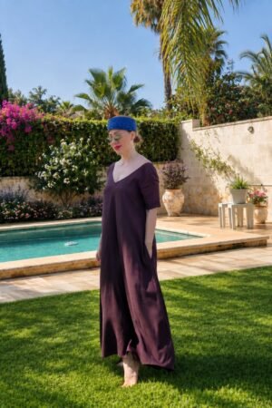 Mujer posando en un jardín con piscina luciendo un vestido largo fluido de color marrón chocolate con doble escote en V y manga corta, de la marca OH.LA.