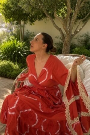 Mujer luciendo el vestido largo Susani en tono teja con estampado tie-dye blanco, mangas acampanadas con blonda de encaje crema y escote en pico cruzado.