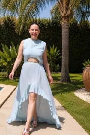 Mujer de espaldas luciendo el Vestido Besanti Aqua de OH.LA junto a una piscina, destacando el gran escote trasero y el bajo asimétrico con volantes.