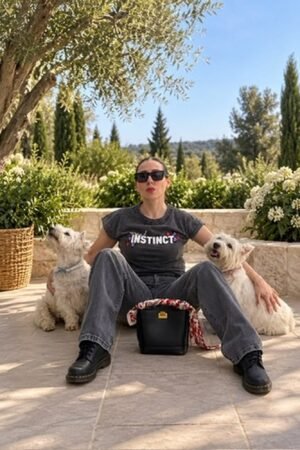 Mujer sentada con la camiseta Animal Instinct de OH.LA en gris y dos perros