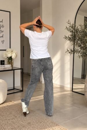 Mujer con vaqueros grises con perlas y piedras de OH.LA y camiseta blanca
